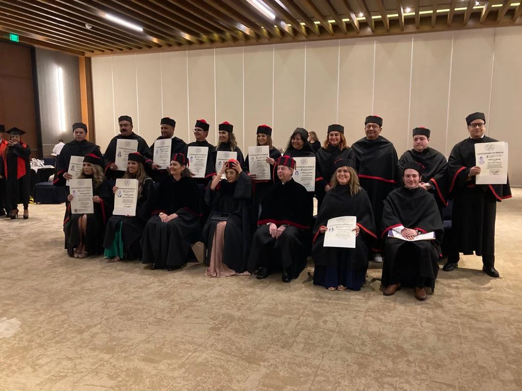 Generación de egresados de IUAF con toga muestra sus diplomas en un salón