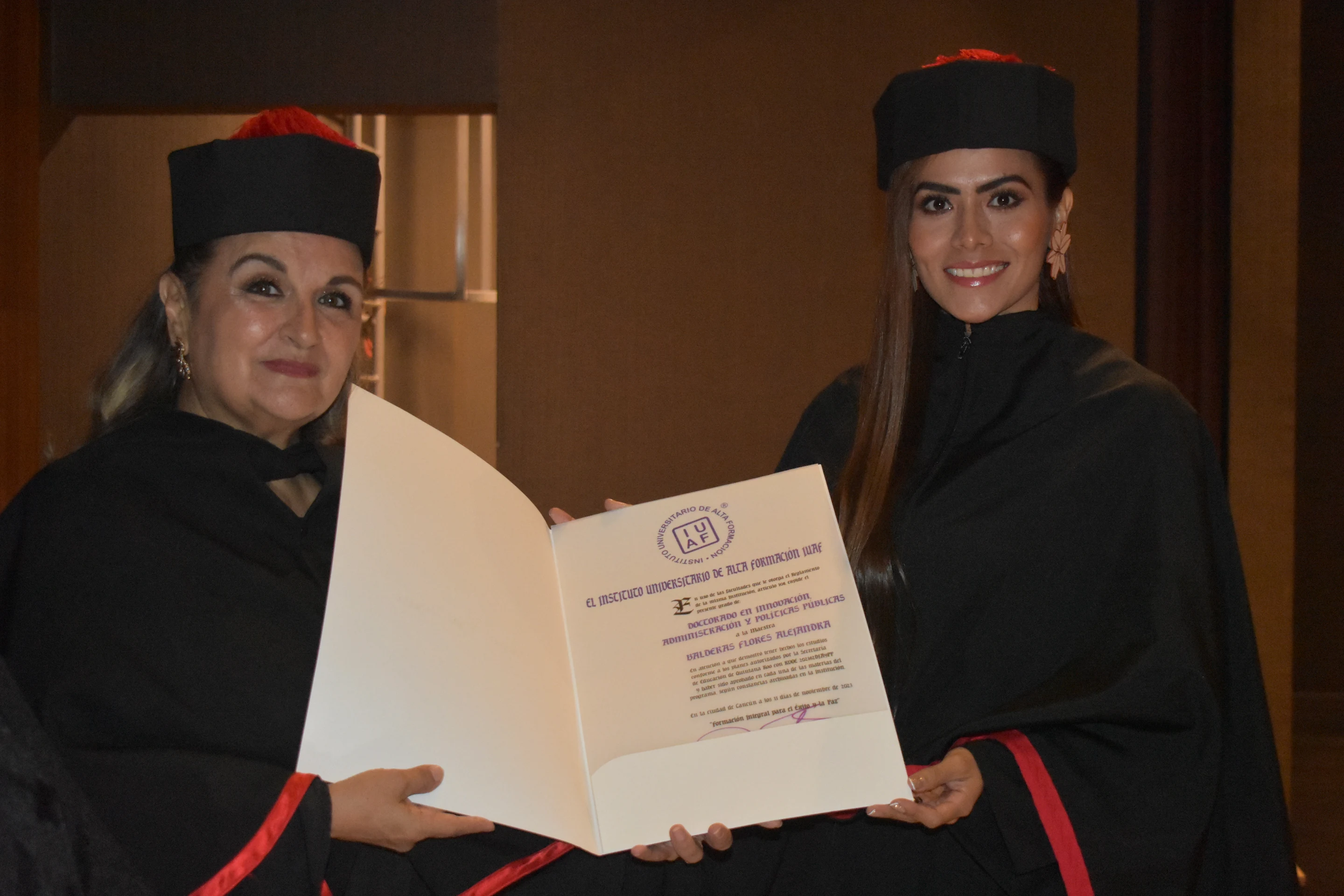 Una académica entrega el diploma abierto a una egresada IUAF