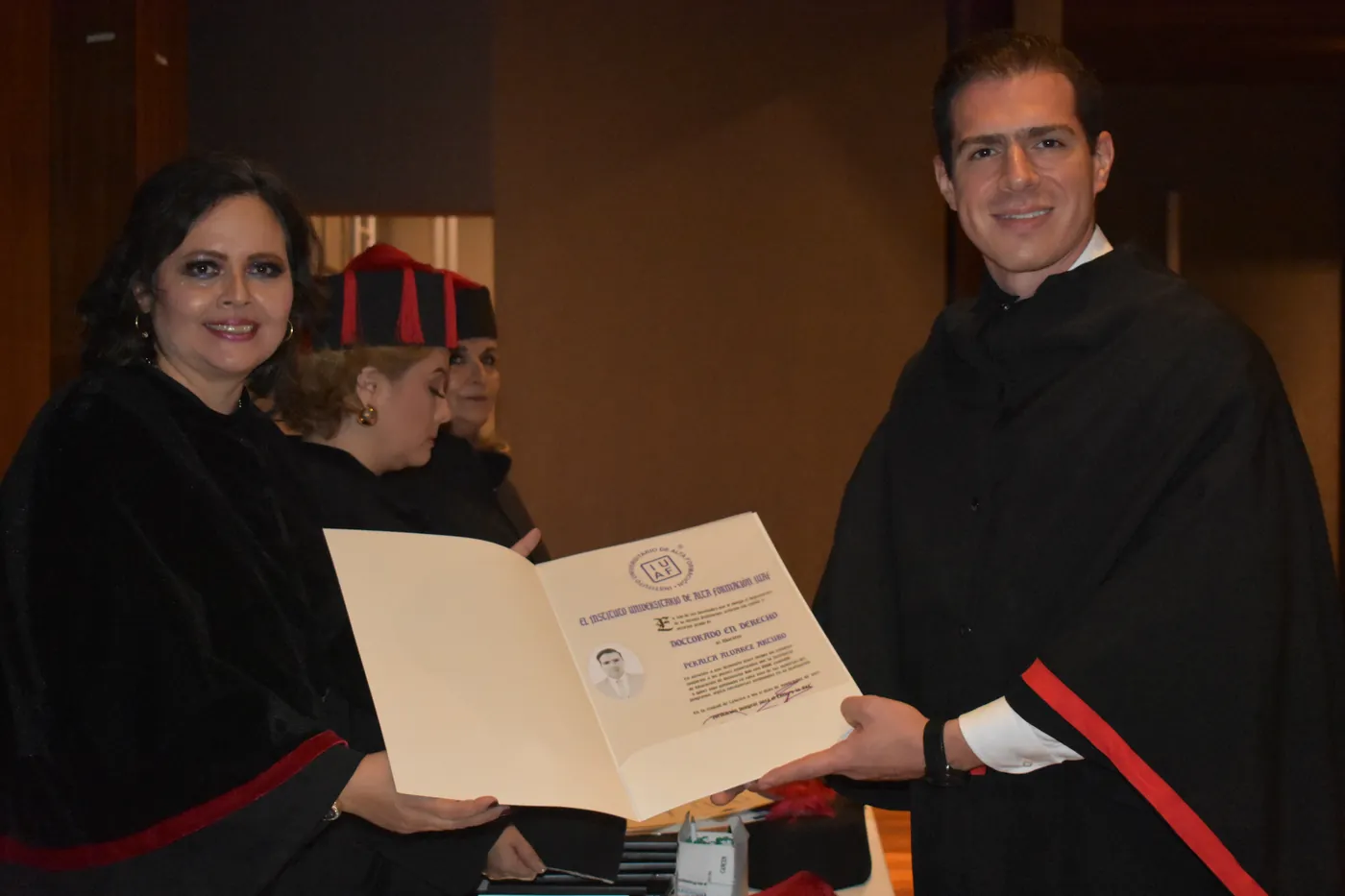 Una académica de IUAF entrega su diploma de Doctorado en Derecho a un egresado